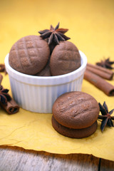 Chocolate cookies, cinnamon sticks and star anise on yellow background.