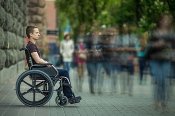 The invalid man sit in the wheel chair in the crowd stream at sidewalk