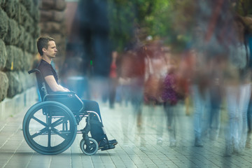 The invalid man sit in the wheel chair in the crowd stream at sidewalk