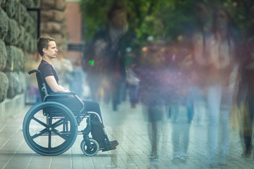The invalid man sit in the wheel chair in the crowd stream at sidewalk