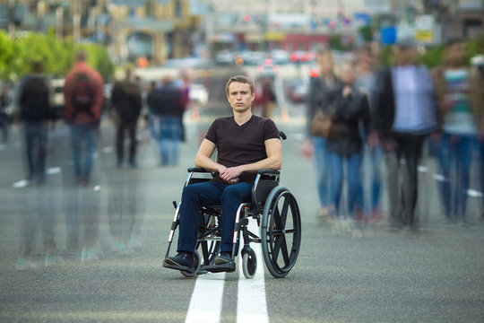 The invalid man sit in the wheel chair in the crowd stream at the road
