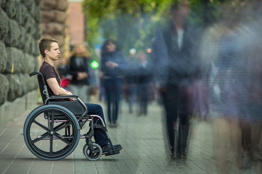 The invalid man sit in the wheel chair in the crowd stream at sidewalk