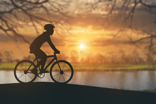 Silhouette of a man on muontain bike on public park at sunset.