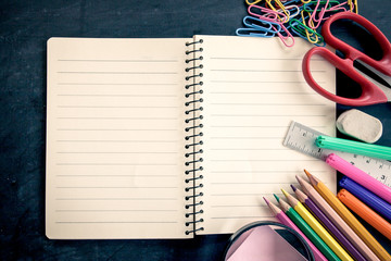 School supplies on blackboard background in vintage color tone