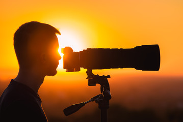 The man use the camera against the background of sunset