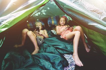 Boy and girl in a tent with mobile phones