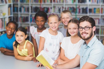 Teacher and kids reading book in library 