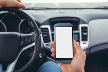 Young man driving a car with a phone in his hand. Multitasking. Don't text and drive