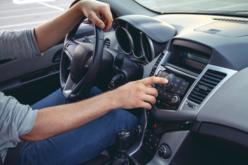 Naklejka premium Car dashboard. Radio closeup. Man sets radio