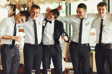 Groom and groomsmen have fun while posing in the restaurant