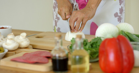 Close up on female hands cutting fresh onion or other starchy white food on table