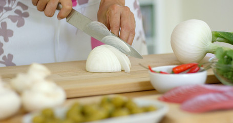 Close up on female hands cutting fresh onion or other starchy white food on table