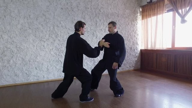 Training in the hall. Two men practicing the elements of tai chi. 4K