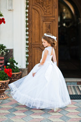 Portrait of cute little girl on white dress and wreath on first
