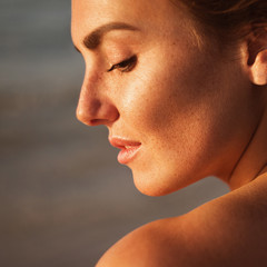Obraz premium portrait of beautiful young woman with freckles standing on the beach background 