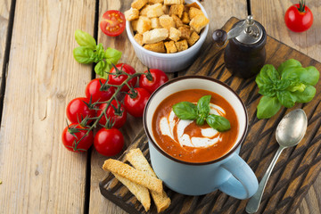 Tomato soup in a ceramic cup on the old wooden background. Selective focus.