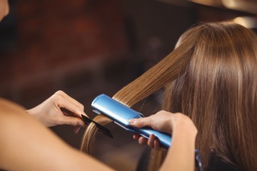 Female hairdresser straightening the hair of a client
