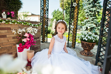 Portrait of cute little girl on white dress and wreath of first