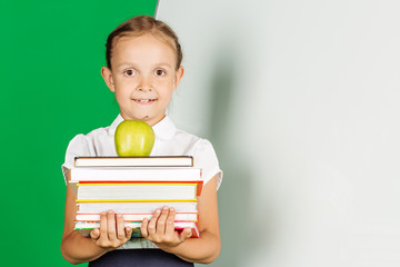 girl in a school uniform holding a stack of books and green apple