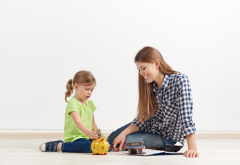 Family savings concept. Young woman with her little daughter planing new flat purchase, sitting on...