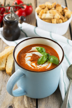 Tomato soup in a ceramic cup on the old wooden background. Selective focus.