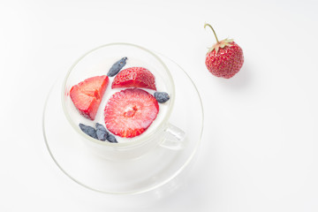 Milk fruit dessert with strawberries and honeysuckle in a cup.