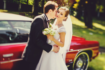Bride looks serious being kissed by a groom behind old American