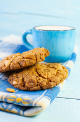 Cereal biscuits and cup of milk on a blue wooden surface.