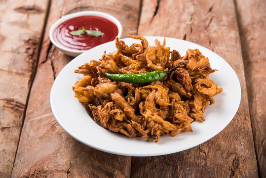 Crispy onion bhaji or kanda bhaji or fried onion pakore or pakode, delicious street food, favourite indian snack in monsoon served with hot tea