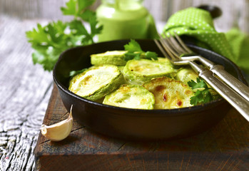 Fried zucchini in a skillet with spicy green sauce.