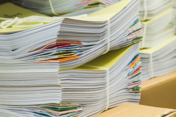 Pile of documents on desk stack up high waiting to be managed