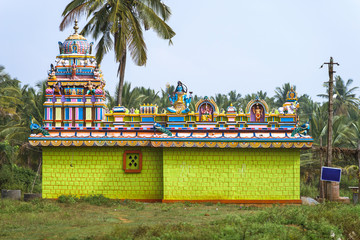 Small colorful hindu temple dedicated to Lord Shiva in the Karnataka countryside, India. Side view.