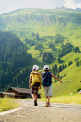 Two little children, boy brothers with backpacks travel on the r