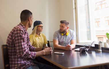Photographer has conversation with clients while sitting in restaurant. Three persons discussing topic of photo shooting on meeting in vegan caffe.