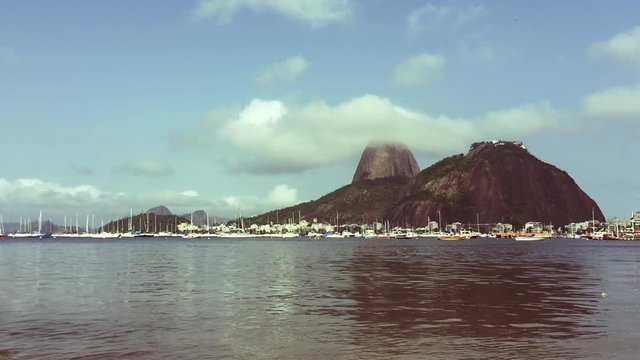 Classic daytime scenic profile view of Pao de Acucar Sugarloaf Mountain in Rio de Janeiro, Brazil standing above Guanabara Bay from the shore of Botafogo Beach