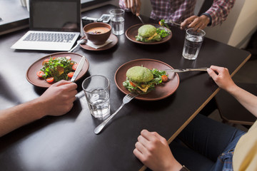 Closeup picture of vegan dishes represented onblack wooden table in vegan restaurant or cafe while business people communicating.