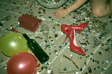 Heels, balloons, sparkles and bottle on the floor after party