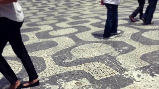 Pedestrians walk on the iconic sidewalk tile pattern in the downtown business district of Centro Rio de Janeiro, Brazil 