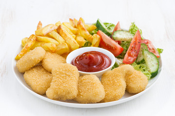 chicken nuggets, french fries and vegetable salad in plate