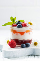 dessert with jam, cream and fresh fruit in a glass jar, closeup