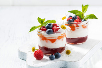 dessert with jam, cream and fresh fruit in a glass jars 