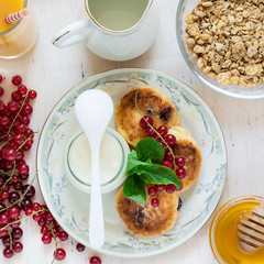 Healthy breakfast: cheesecakes, muesli, yogurt, honey, fresh berries and juice on white wooden background