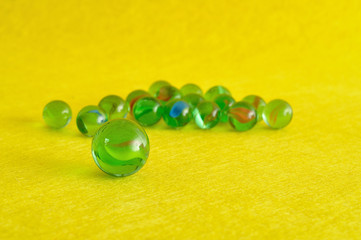 A collection of marbles isolated on a yellow background with shallow depth of field