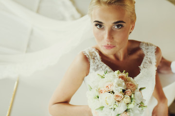 Bride looks straight into the camera leaning on the piano