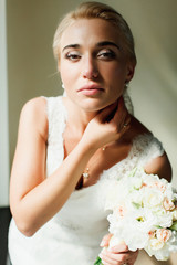 Blond bride looks gorgeous standing in the lights of midday sun