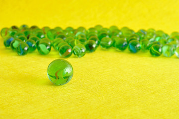 A collection of marbles isolated on a yellow background with shallow depth of field