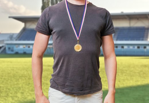 Sportsman is standing in stadium and wearing golden medal.