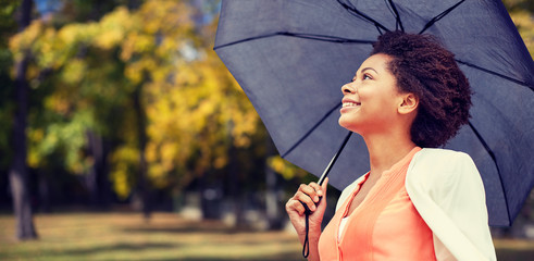 happy african woman with umbrella in autumn park 