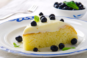 Homemade cake with cream, blueberries and mint on white background