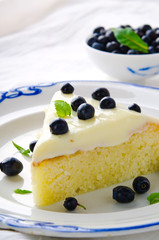 Homemade cake with cream, blueberries and mint on white background